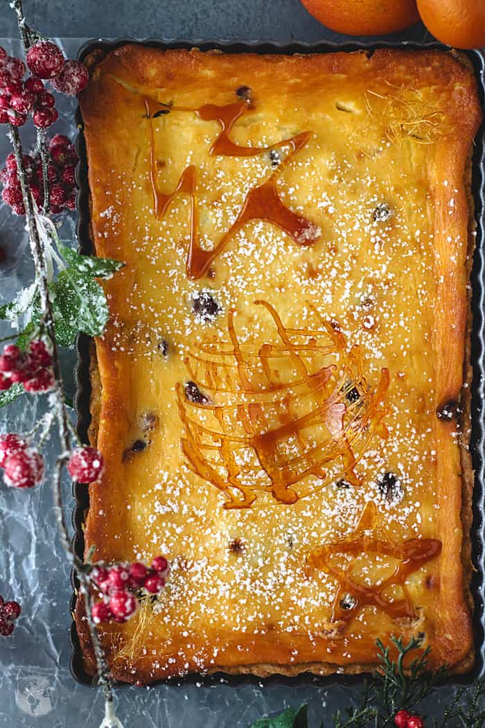 An overhead shot of cranberry tart with caramel garnishes and Christmas decorations.