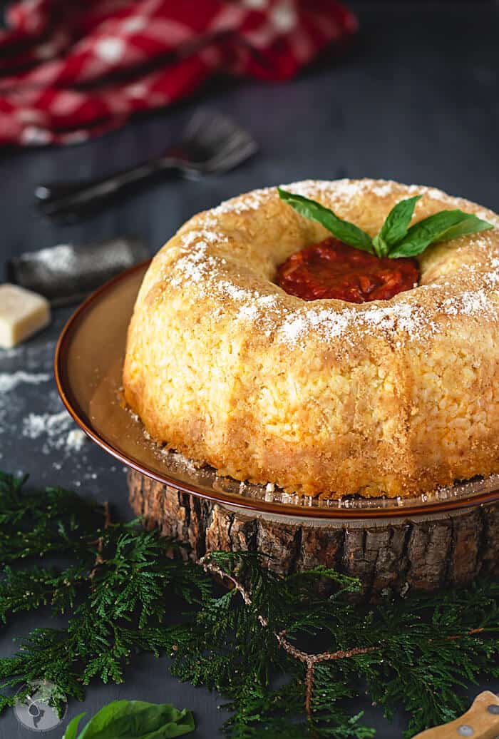 A straight shot of timbale on a plate placed on a round wooden plank