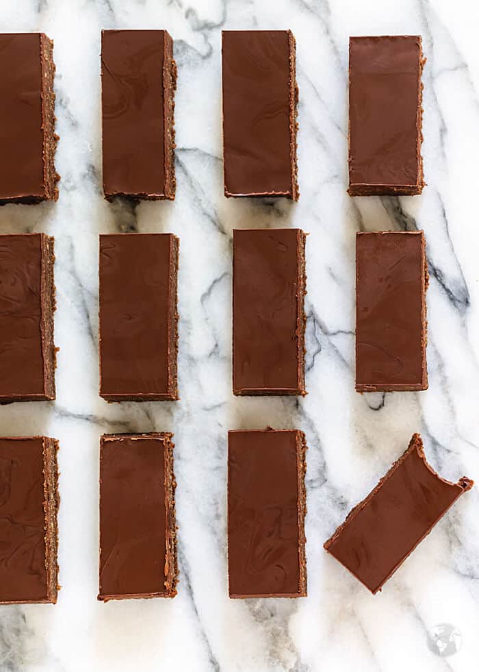 Straight rows of rum bars on a white marble surface with the bottom right bar crooked and bitten into.