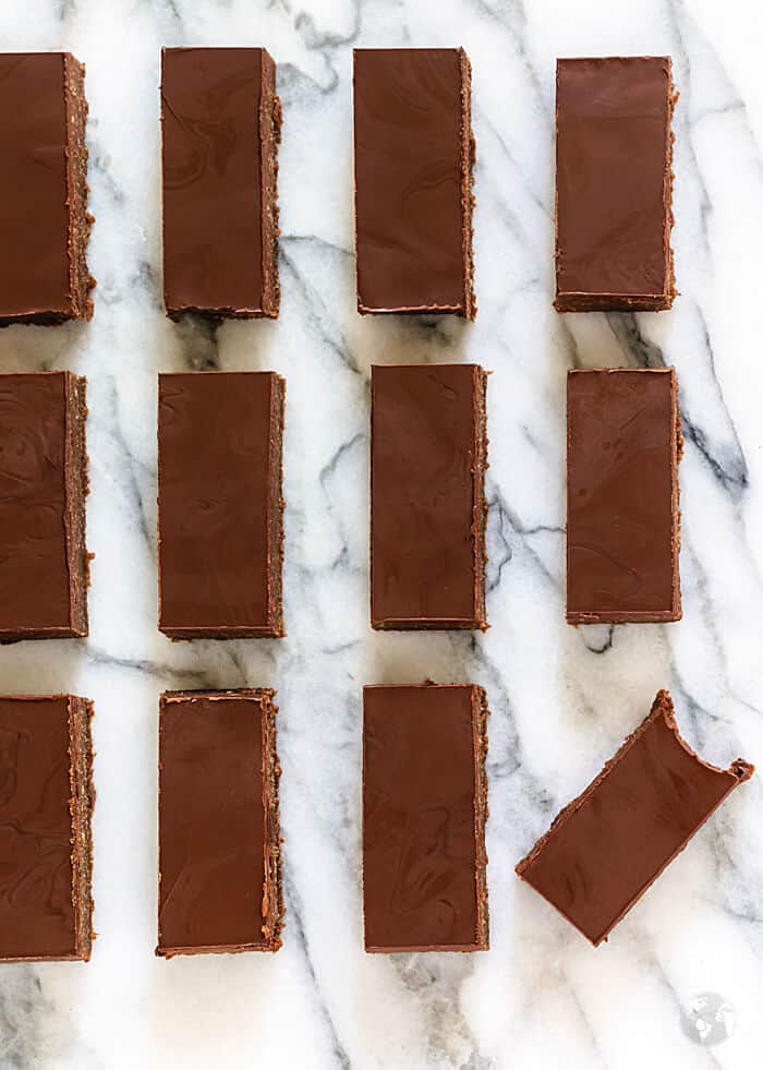 Straight rows of rum bars on a white marble surface with the bottom right bar crooked and bitten into. 