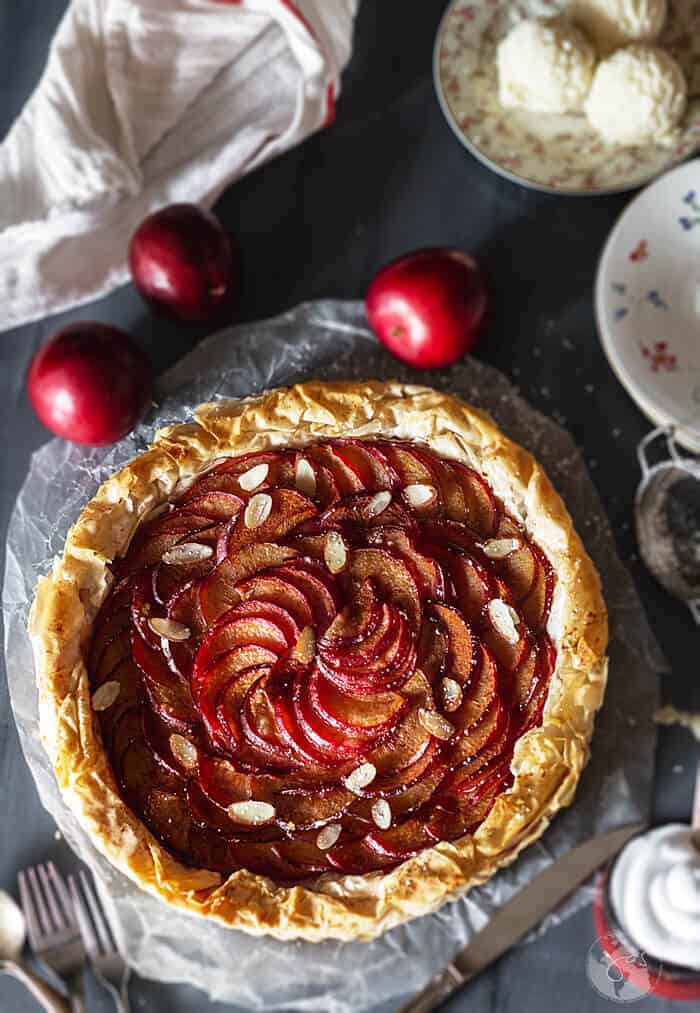 An overhead shot of plum tart on a dark background.