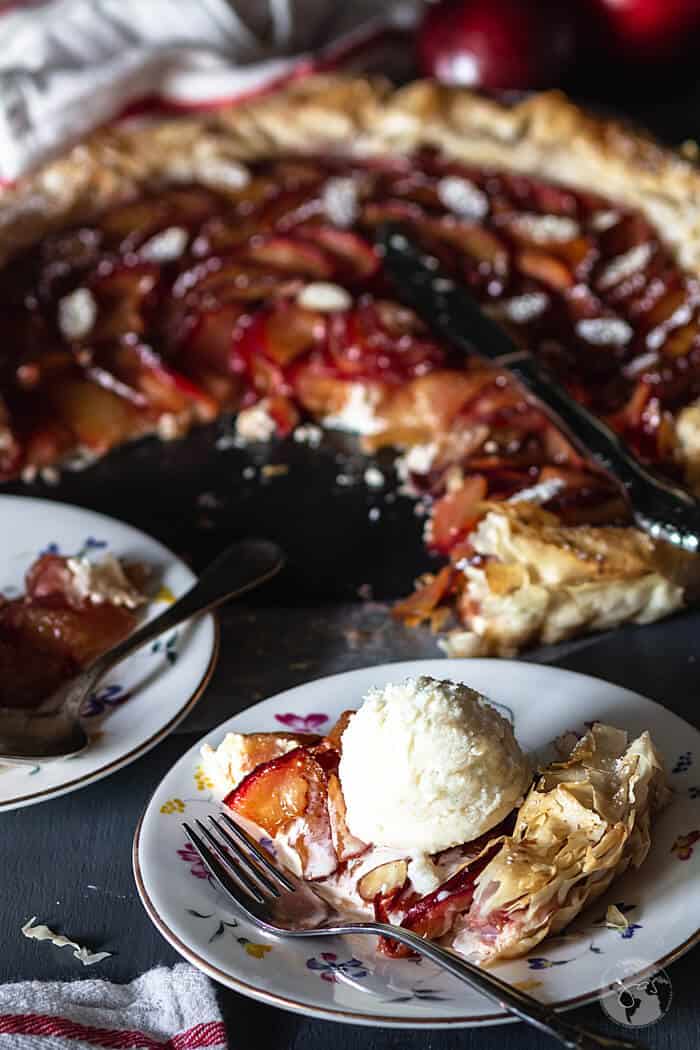 A slice of rustic plum tart with ice cream.