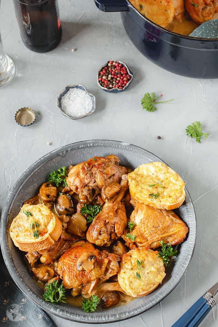 A bowl of Chicken in Beer Sauce with Welsh Rarebit on a gray background- Coq à la Bière.