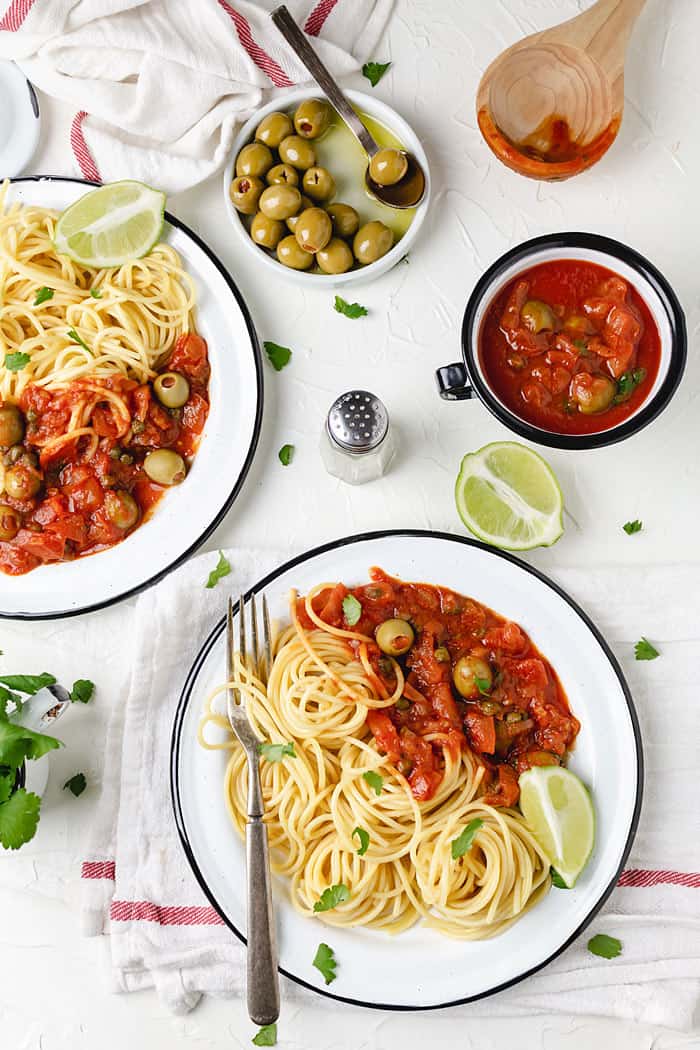 Spaghetti on two plates with a side of Veracruz sauce.