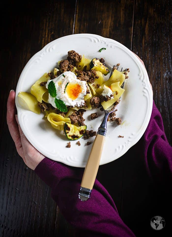 A person setting a plate of Turkish pasta dish on the table.