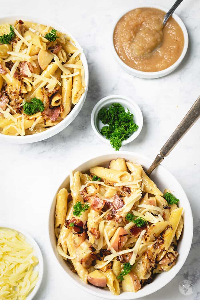 Two bowls of mac and cheese recipe from Switzerland with a serving of applesauce.