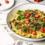 Pasta frittata in a white skillet with cherry tomatoes