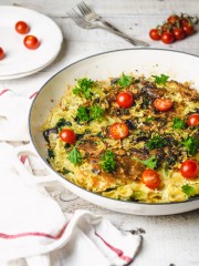 Pasta frittata in a white skillet with cherry tomatoes