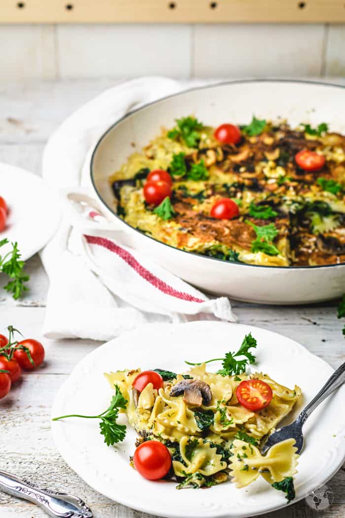 A white skillet and a plate with pasta frittata Spanish stovetop dish.