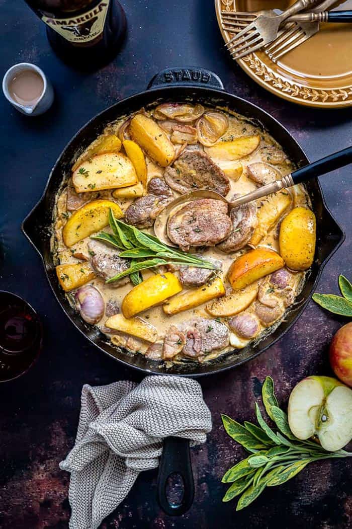 Potatoes and pork dish in a iron pan on the blue background.