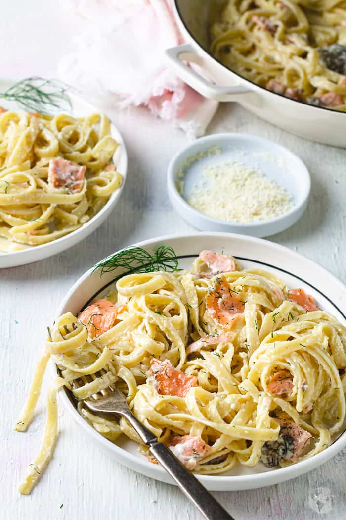 Flat lay of fettuccine with smoked salmon in two plates on a table..