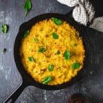 Corn pie skillet dish on a gray background with tan kitchen towel.