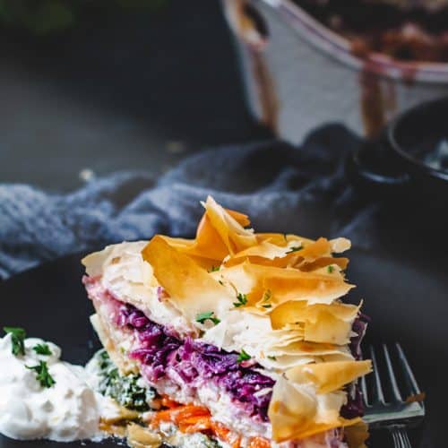 A moody shot of the slice of vegetable and cheese pie on a plate.