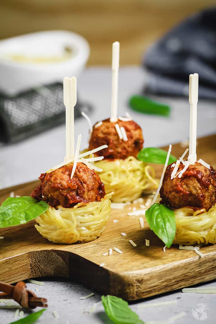 Spaghetti nests appetizer with meatballs with toothpicks.