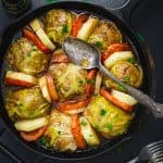 An overhead shot of Palestinian Stuffed Savoy Cabbage Rolls in a cast Iron skillet on a black background