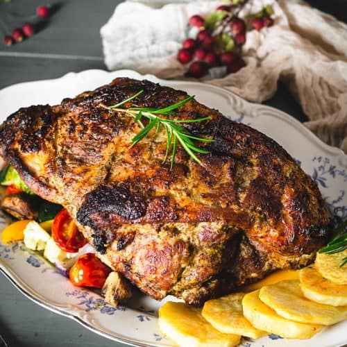 pork roast on a serving platter with roasted vegetables