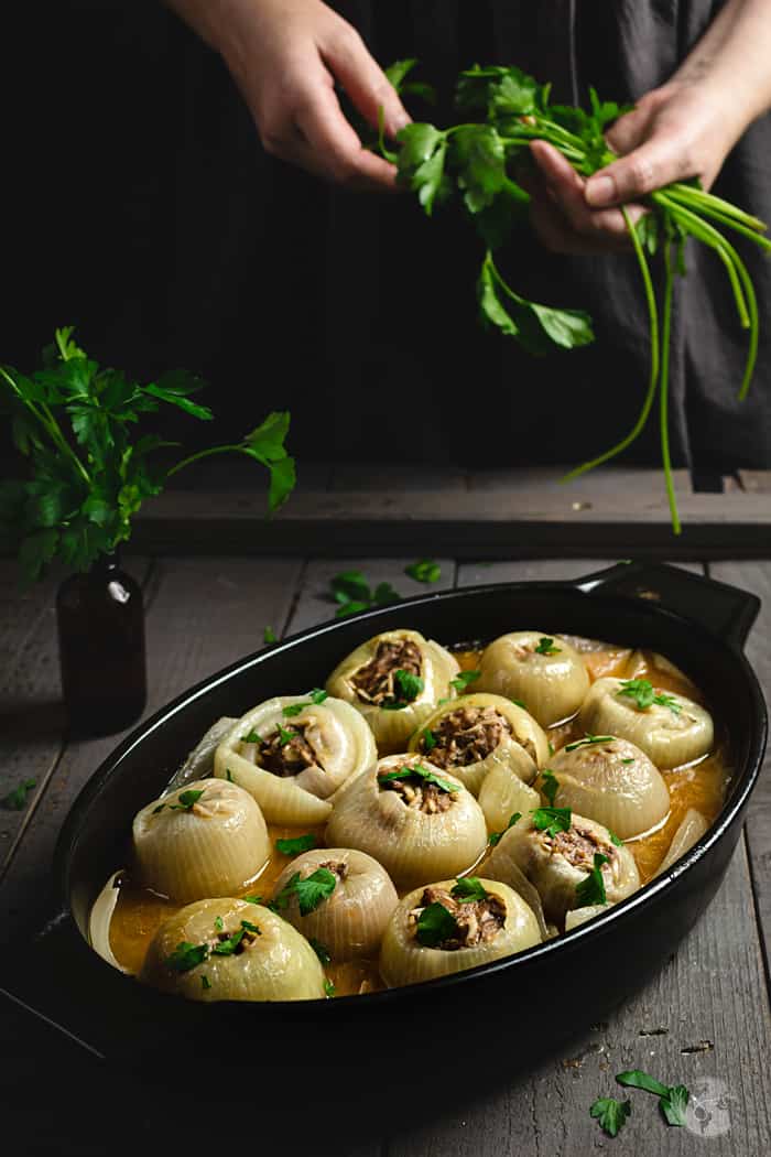 Stuffed onions in a black oval dish on a dark gray