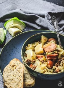 A bowl of food sitting on a plate with bread slices.