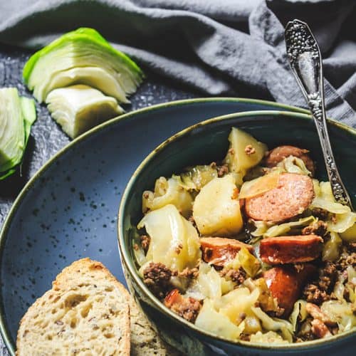 A bowl of food sitting on a plate with bread slices.