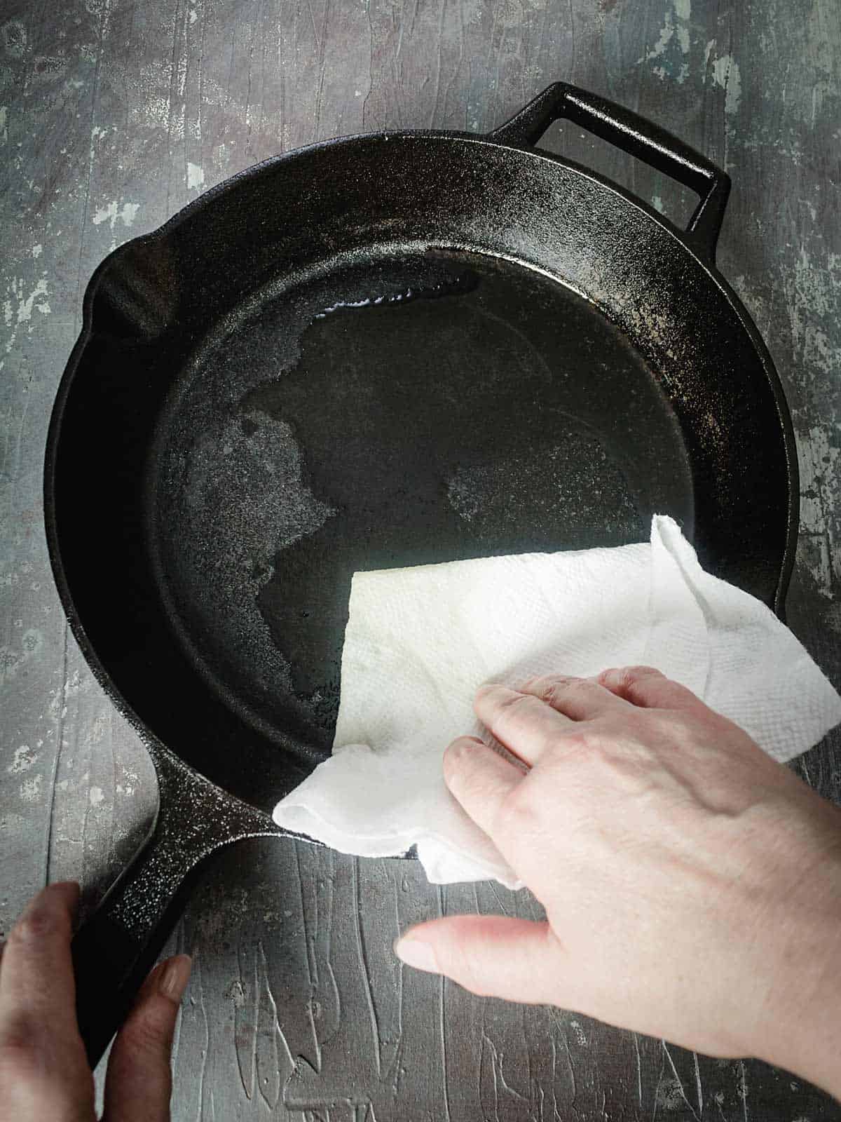 Rubbing oil on the cast-iron pan with paper towel.