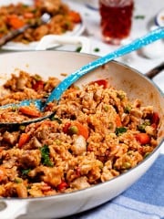 Rice with vegetables and pieces of chicken thighs in a white enamel cast-iron skillet