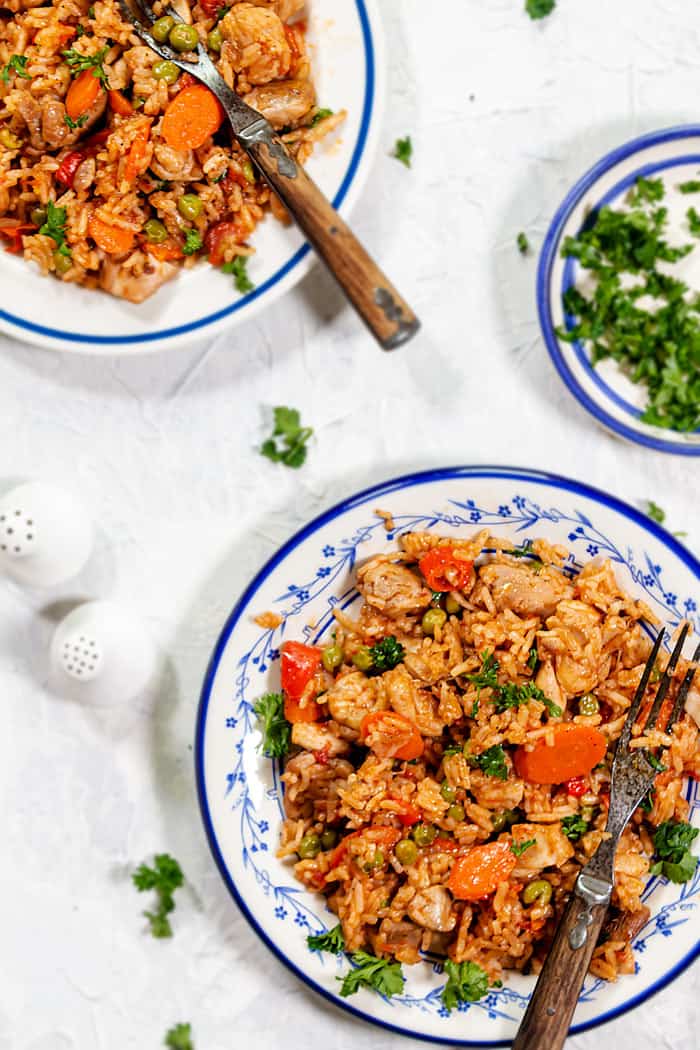 Overhead of two plates with rice dish on a white tablecloth.