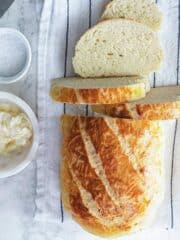 Loaf of yeastless bread sliced half-way on a napkin with butter.