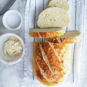 Loaf of yeastless bread sliced half-way on a napkin with butter.