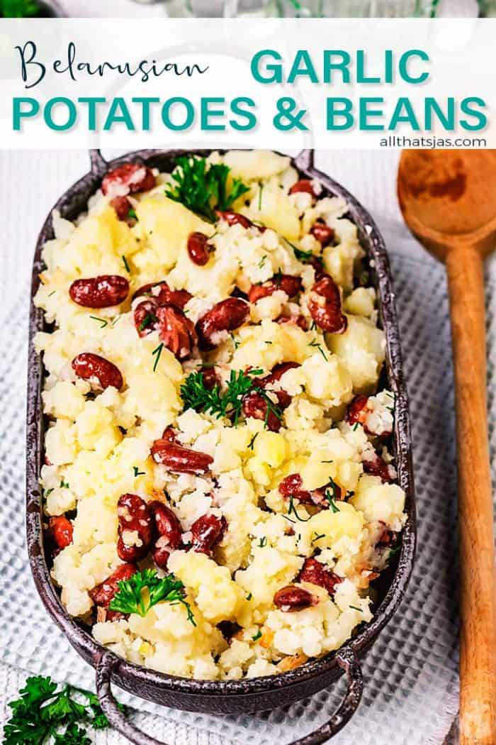 An oval dish with smashed potatoes and red kidney beans on a light blue background and wooden spoon.