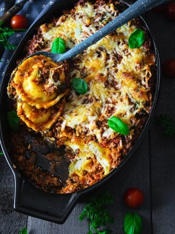 A dish with ravioli on a spoon and tomatoes