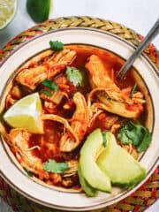 Red and green bowl with chunky chicken soup and a spoon - overhead