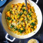 An overhead shot of barley risotto with butternut squash in a dark background