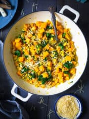 An overhead shot of barley risotto with butternut squash in a dark background