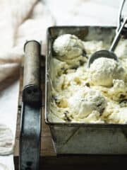 A shot of a loaf tin filled with no-churn rum and raisins gelato with ice cream scoop.