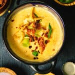 An overhead photo of the cheese soup topped with bacon bits and French fried onions and surrounded with small bowls of garnishes