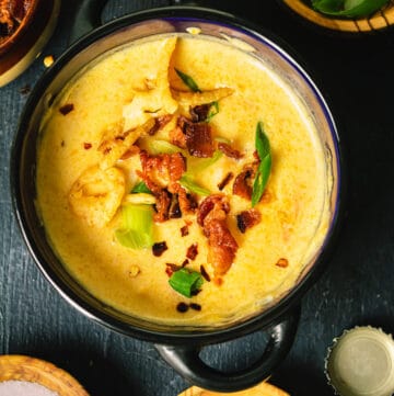 An overhead photo of the cheese soup topped with bacon bits and French fried onions and surrounded with small bowls of garnishes