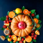 An overhead shot of fillo bundt in the middle of fruit and veggie wreath on a dark background