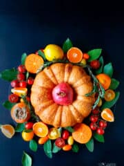 An overhead shot of fillo bundt in the middle of fruit and veggie wreath on a dark background