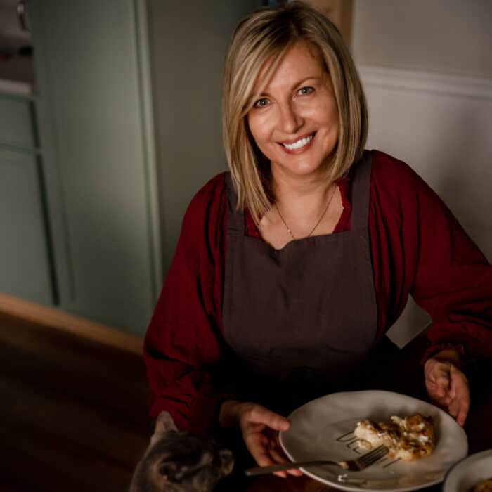 A woman sitting at the kitchen table with a plate of food.