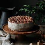 Tiramisu cheesecake on a cake stand with kitchen towel on a rustic table