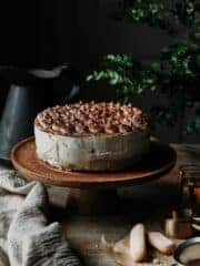 Tiramisu cheesecake on a cake stand with kitchen towel on a rustic table