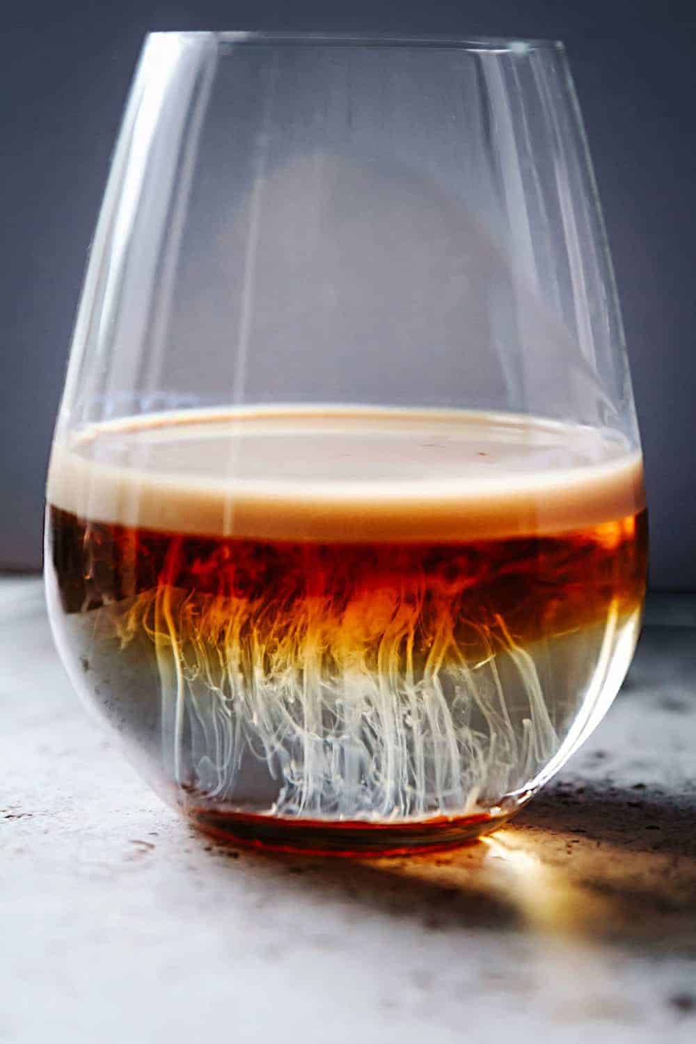 A shot glass sitting on the counter with cocktail resembling jellyfish.