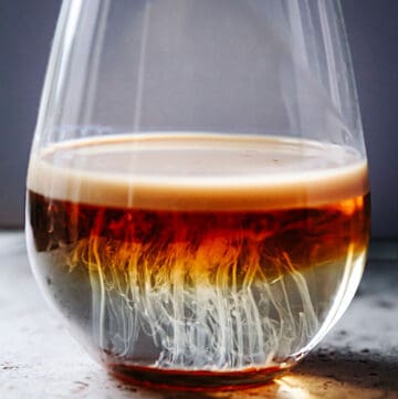 A shot glass sitting on the counter with cocktail resembling jellyfish.