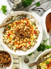 Kushari dish in a bowl sitting on the table with other condiments and food.