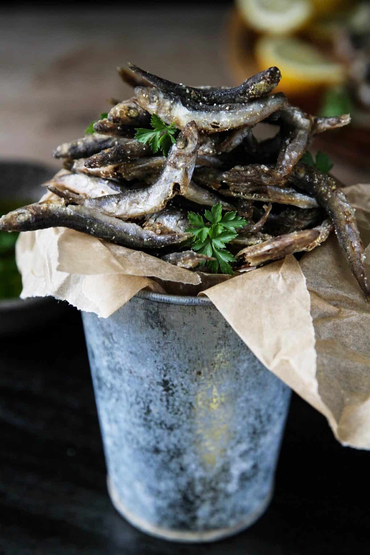 A close up of fried smelt fish in a small bucket.