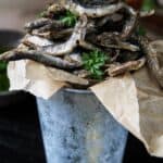 A close up of fried smelt fish in a small bucket.