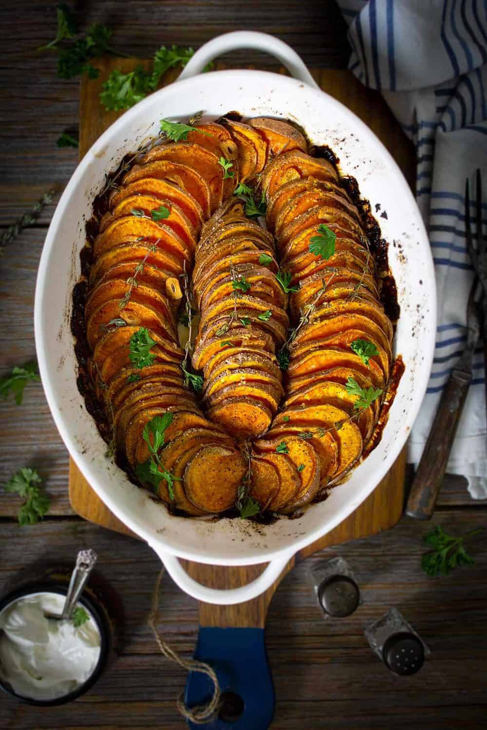 An oval dish with slices of crispy roasted sweet potatoes sitting on a table.