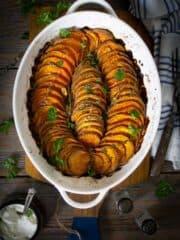 An oval dish with slices of crispy roasted sweet potatoes sitting on a table.