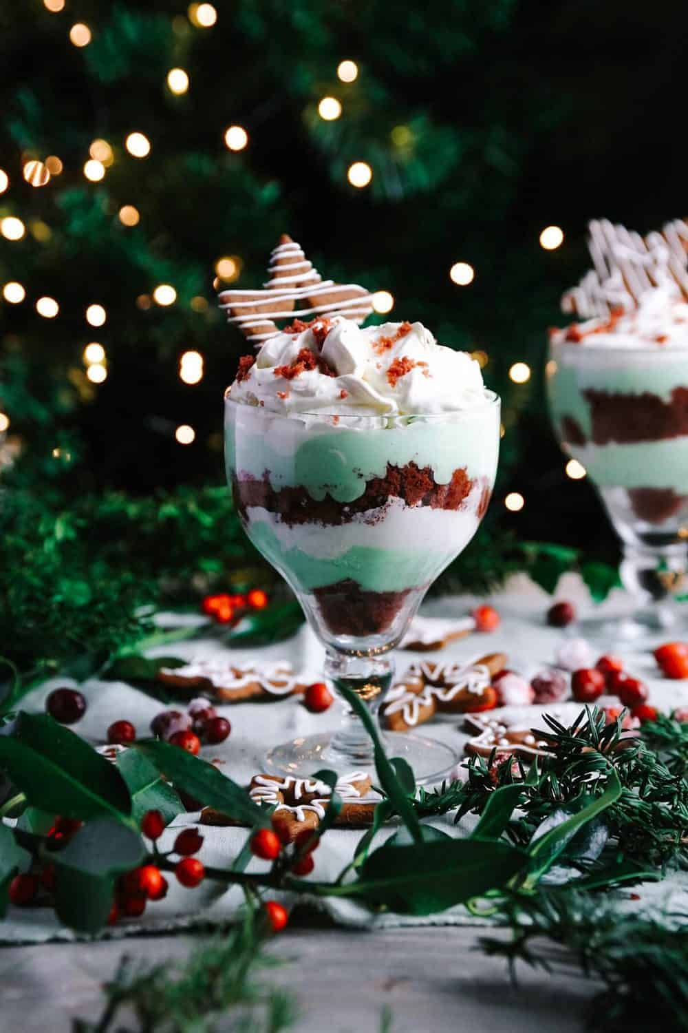 A glass with dessert trifle sitting on a table with Christmas decorations