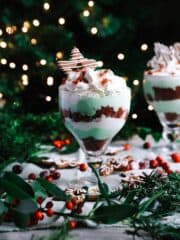 A glass with dessert trifle sitting on a table with Christmas decorations